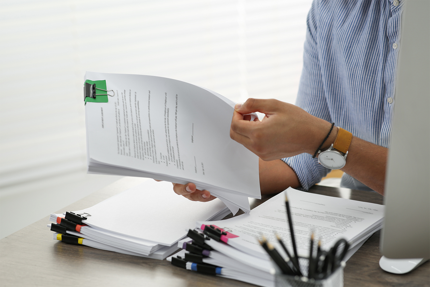Man working with documents at wooden table in office, closeup